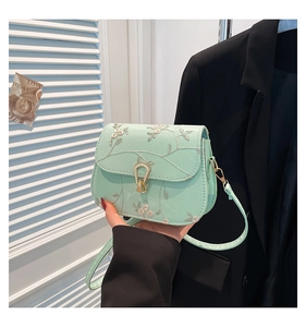 Détail du sac bandoulière vert menthe avec broderie florale et boucle dorée élégante