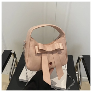 Détail du sac rose clair à nœud avec chaîne argentée et texture en cuir synthétique brillant