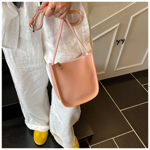 Detail of pink lychee grain leather crossbody bag with adjustable strap and metal zipper