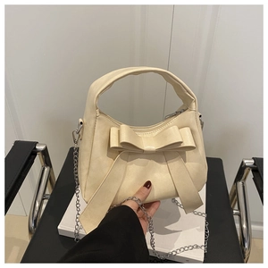 Détail du sac à main blanc crème avec grand nœud et bandoulière en chaîne argentée