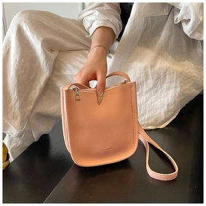 Close-up of beige lychee leather bucket bag featuring a zipper and embossed brand logo