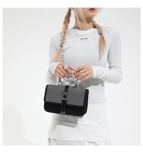 Detail of grey and black patchwork handbag featuring a twisted silver metal handle