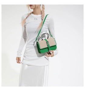 Detail of green leather and beige canvas contrast bag with unique silver metal handle