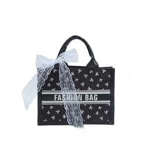 Black quilted tote bag with white bows and Fashion Bag text on white background