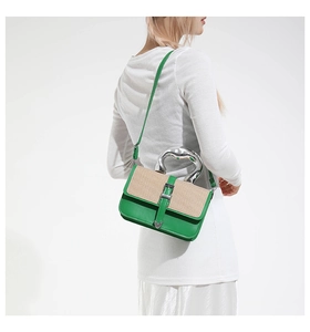 Detail of green leather handbag with straw weaving and silver heart metal buckle