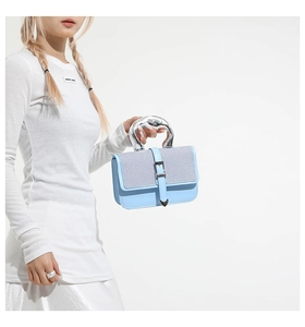 Detail of light blue crossbody bag with liquid metal handle and heart charm accents