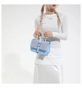 Close-up of light blue handbag featuring woven texture and metallic silver handle
