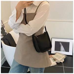 Close-up of black litchi pattern leather bucket bag worn on shoulder by a model