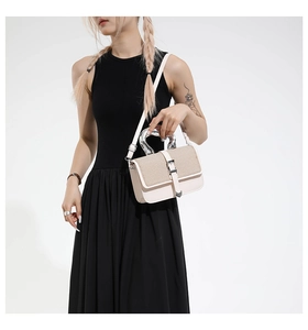 Detail of white square bag featuring silver U-shaped handle and woven texture texture finish