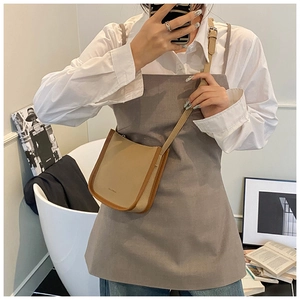 Detail of khaki leather bucket bag with brown trim and adjustable slim shoulder strap