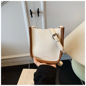 Detail of cream bucket bag in lychee leather texture with adjustable strap and logo