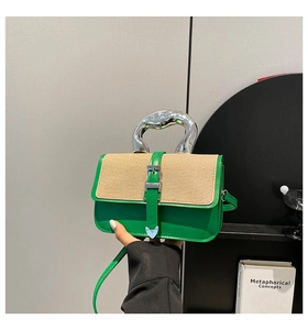 Detail view of green handbag with silver irregular metal handle and woven texture lid