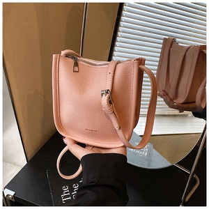 Close-up of pink lychee grain leather bucket bag with silver zipper and adjustable strap
