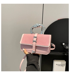 Close-up of pink crossbody bag with unique silver handle and heart-shaped metal buckle