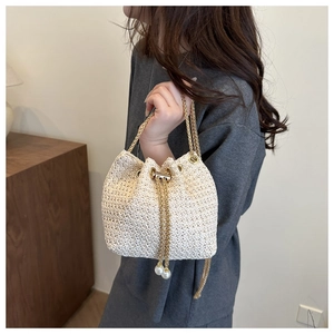 Close-up of woven bucket bag with gold chain and large pearl drawstring details
