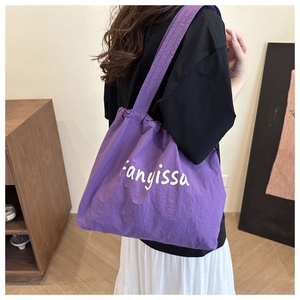 Gros plan du sac fourre-tout en nylon violet avec lettrage fanyissa blanc et large bandoulière