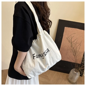 Lifestyle view of a white canvas tote bag with black Fanyissa print and soft texture