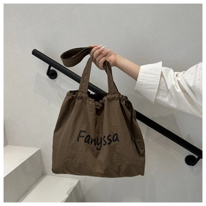 Detail of a Fanyssa brown nylon drawstring tote bag shown in a minimalist outdoor setting