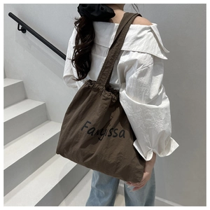 Detailed side view of a large brown drawstring tote bag with Fanissa print and textures