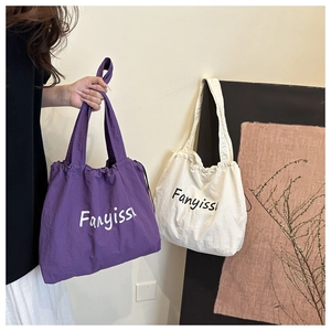 Detail view of purple and beige canvas drawstring tote bags with wide shoulder straps