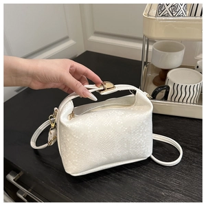 Detailed close-up of white python texture on a chic handbag with premium gold clasp