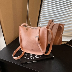 Pink lychee texture bucket bag with thin shoulder strap on desk, 2025 trendy style
