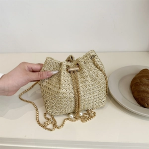 Handwoven straw bucket bag with gold chain strap and elegant pearl drawstring closure