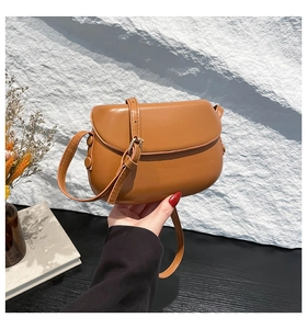 Detail of a brown PU leather saddle bag showing adjustable strap and smooth flap closure