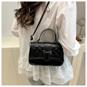 Sac à bandoulière noir matelassé avec boucle argentée porté par un mannequin en intérieur