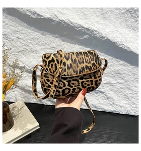Close-up of leopard print saddle bag with adjustable strap and premium brown leather piping
