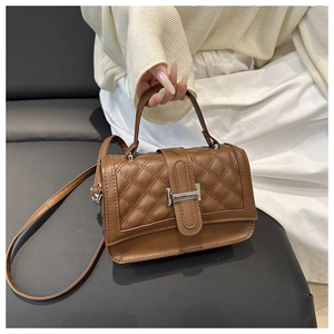 Détail d'un sac à main matelassé marron avec boucle argentée et poignée rigide