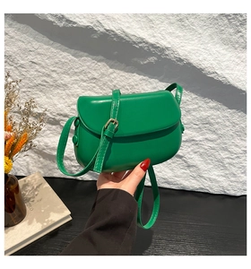 Detailed close-up of emerald green saddle bag featuring a flap closure and adjustable strap