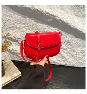Detail view of a stylish red saddle bag with a rounded flap and adjustable strap