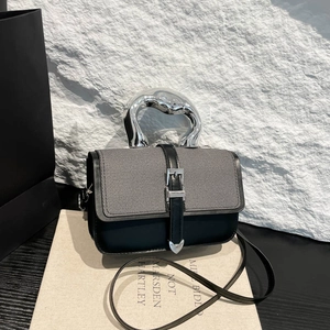 Minimalist grey tweed and black leather handbag featuring a unique silver sculptural handle