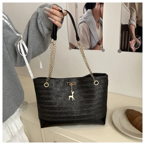 Détail du sac cabas en paille noire avec pendentif cerf doré et poignées en chaîne chic