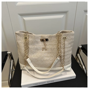 Detailed close-up of cream woven tote bag with straw texture and gold deer charm