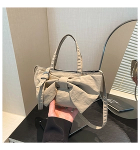 Détail d'un sac à main en nylon kaki avec un grand nœud décoratif et texture plissée