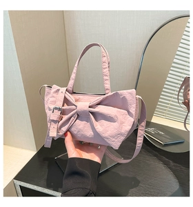 Détail du sac seau rose à nœud papillon avec tissu texturé et bandoulière réglable