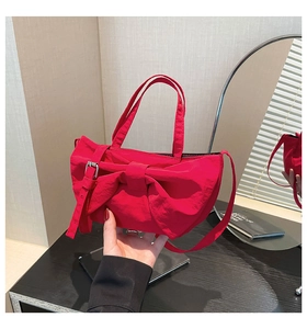 Détail du sac bandoulière en nylon rouge avec grand nœud et boucle argentée ajustable