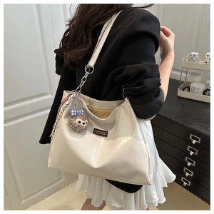 Detail of cream large tote bag with silver chain strap and plush bear charm accent