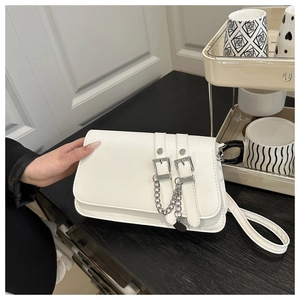 Detail of white baguette bag with silver metal buckles and decorative chain