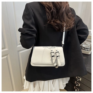 Modern white leather baguette bag with decorative straps and silver chains on a model