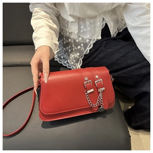 Detail of red baguette bag with silver buckles, chain strap and metallic pendant