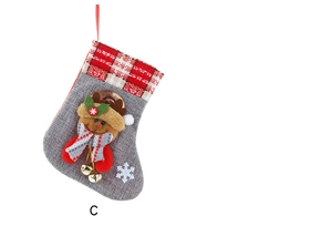 Detail of Christmas stocking in burlap with reindeer motif and golden bell on white background