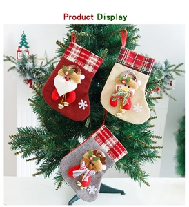Detail of 3D Santa and elk Christmas stockings with bells hanging on a festive tree
