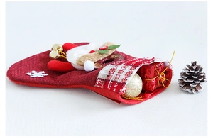 Detail of red burlap Christmas stocking with Santa, bell and festive gift box inside