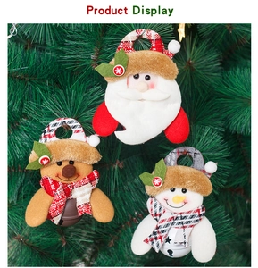 Detail of Christmas plush pendants with Santa and bells hanging on a green tree branch