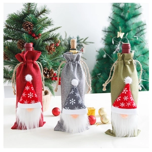 Detalle de tres fundas de yute para botellas de vino con gnomos navideños decorativos