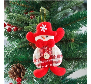 Detail of a handmade snowman ornament with red hat and wooden button on a Christmas tree