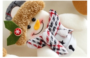 Macro detail of snowman plush bell ornament with plaid scarf and snowflake button decor